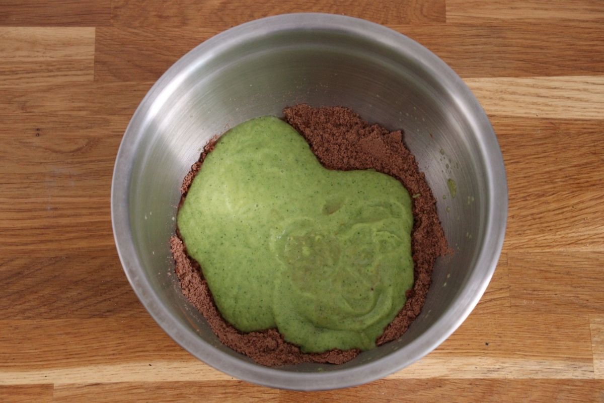 Blended zucchini added to the dry ingredients in a large bowl.