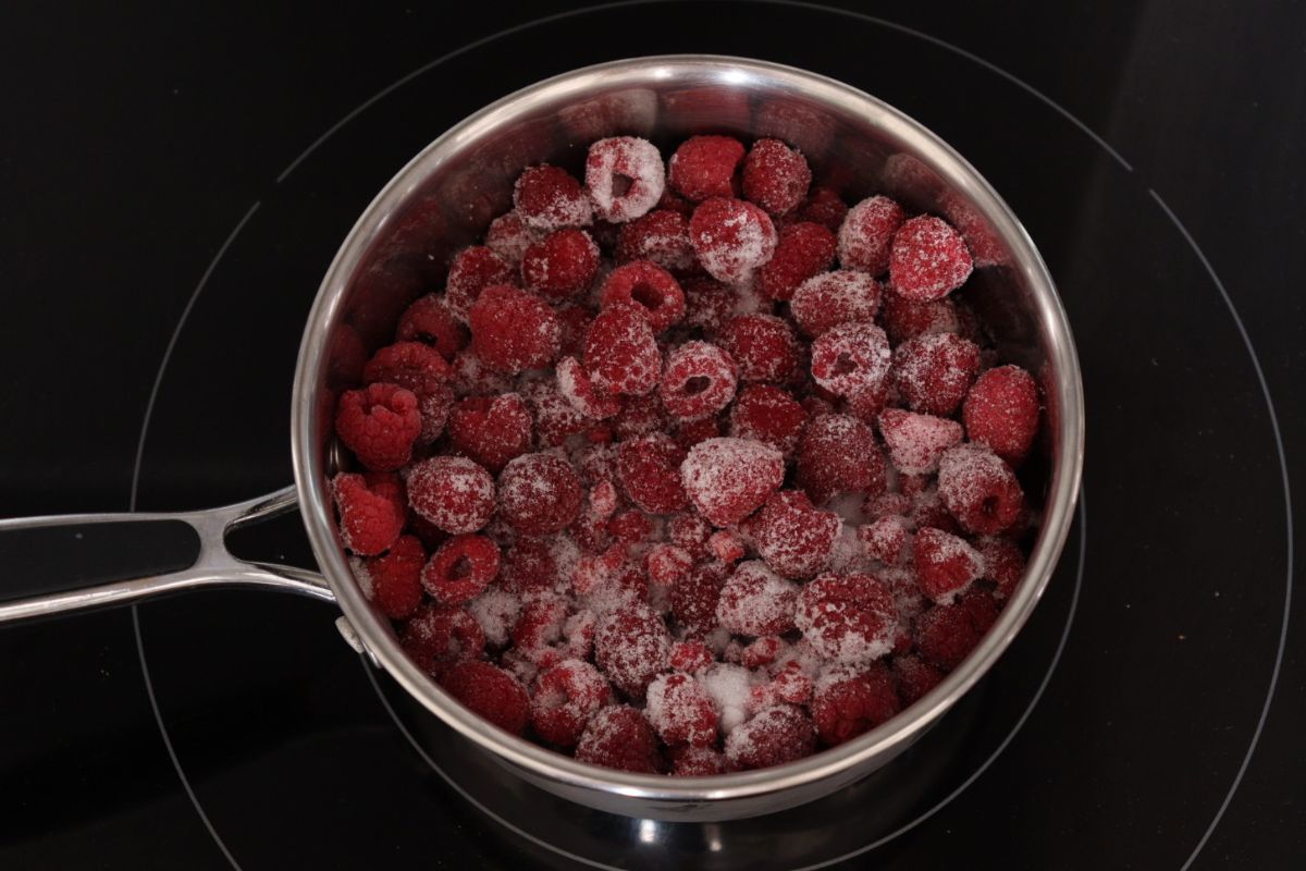 Frozen raspberries and sugar in a sauce pan.