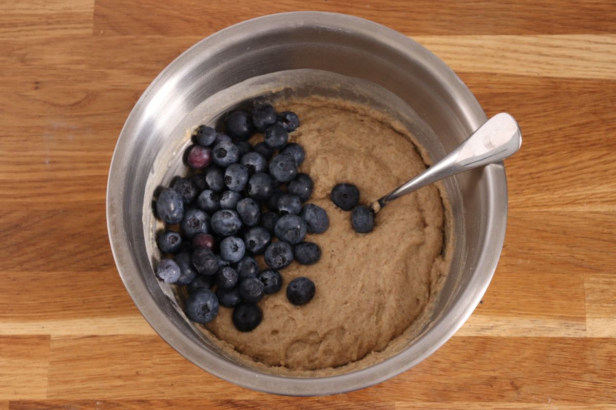 Blueberries added to the dough in the mixing bowl.