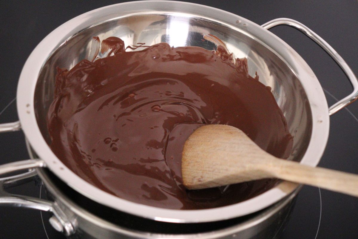Du chocolat fondu dans un bain-marie avec une cuillère en bois.