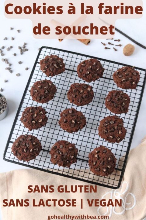 Des cookies à la farine de souchet sur une grille à patisserie avec des pépites de chocolat, des bâtons de cannelle, de la vanille, des clous de girofle et une noix de muscade tout autour.