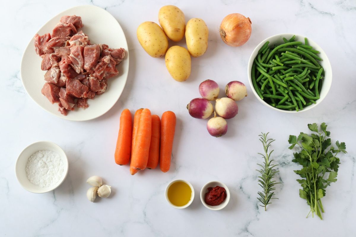 All the ingredients to make French Lamb Navarin spread on a kitchen counter.