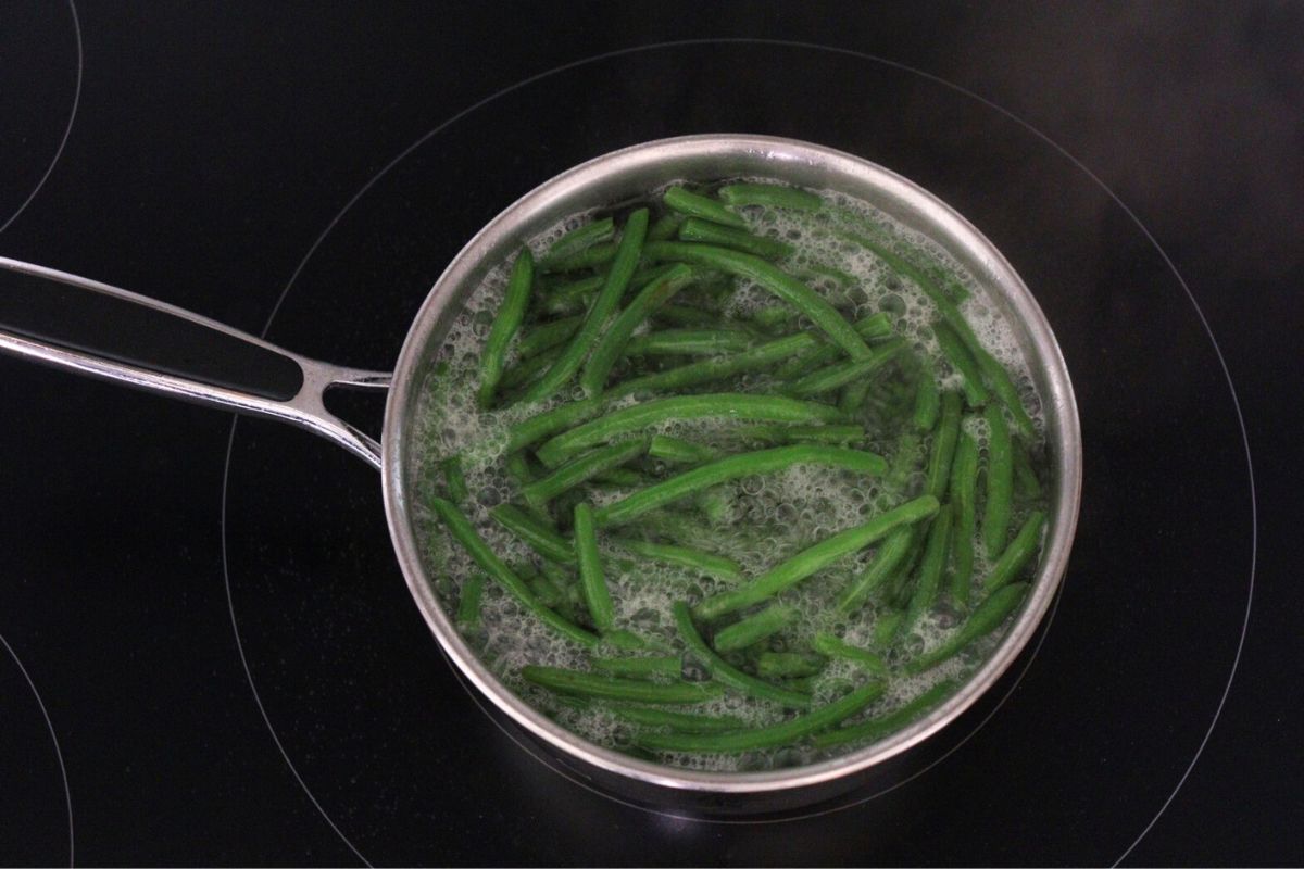 Green beans cooking in a saucepan of water.