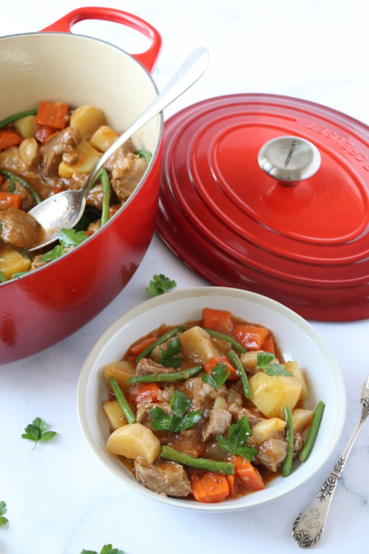 A plate of French Lamb Stew Navarin next to the cast iron Dutch oven where it was cooked. 