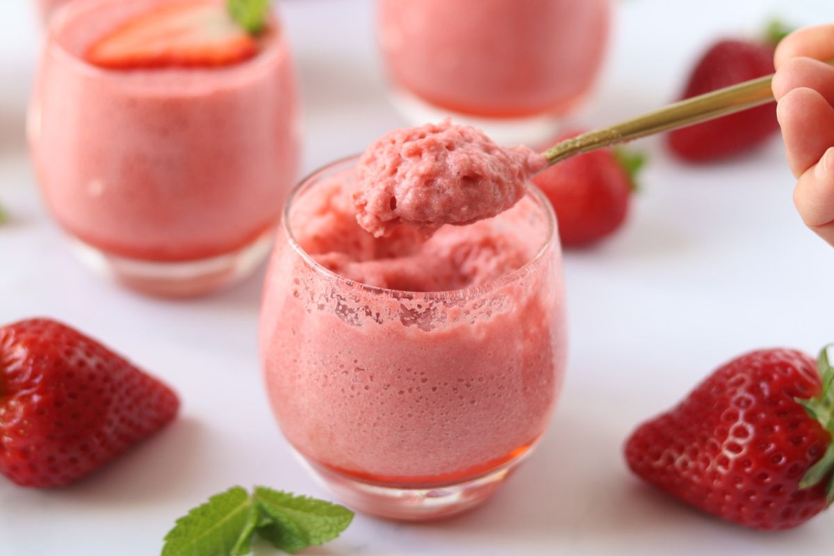 3 glass cups of strawberry mousse and a spoonful of mousse showing the texture.