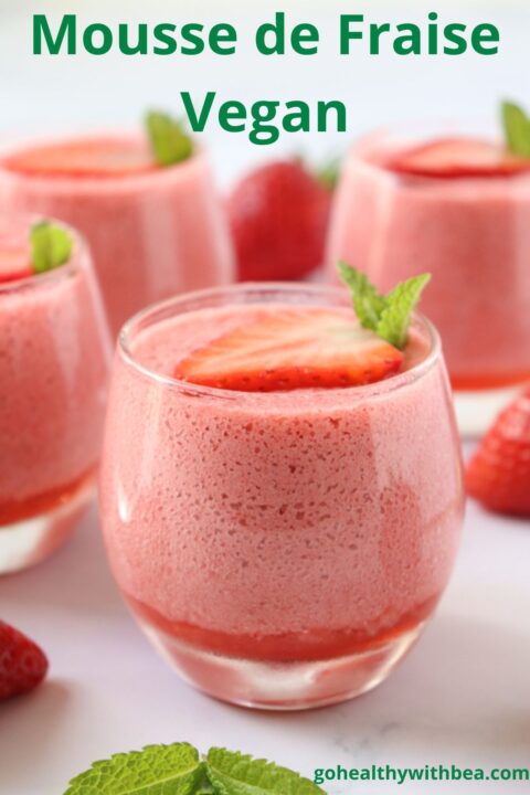 4 verrines de mousse à la fraise décorées d'une tranche de fraise fraîche et de feuilles de menthe.